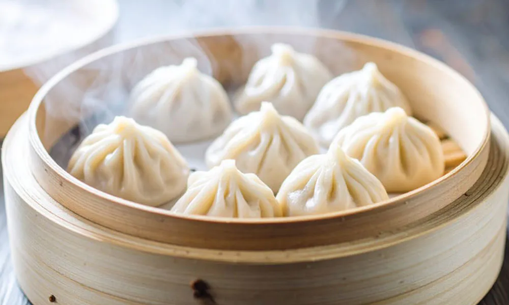Steaming hot soup dumplings (xiaolongbao) in a bamboo steamer at Sumo Ramen CO, a Chinese Restaurant in Fayetteville