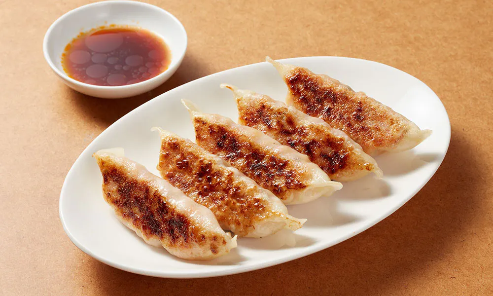 Pan-fried gyoza dumplings with crispy bottoms and dipping sauce at Sumo Ramen CO, a Chinese Restaurant in Fayetteville