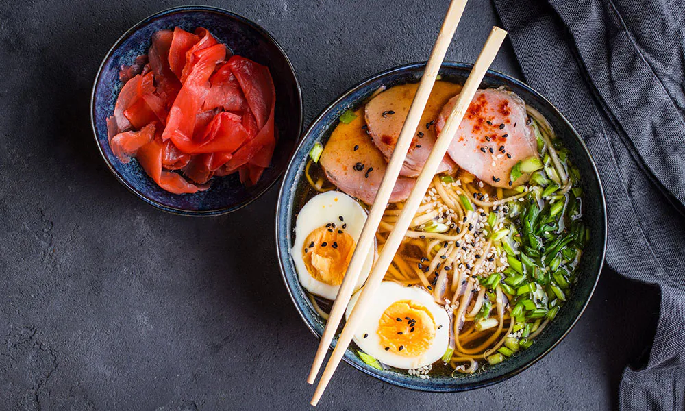 Top-down view of ramen with pork, eggs, scallions, and pickled ginger at Sumo Ramen CO, a Chinese Restaurant in Fayetteville